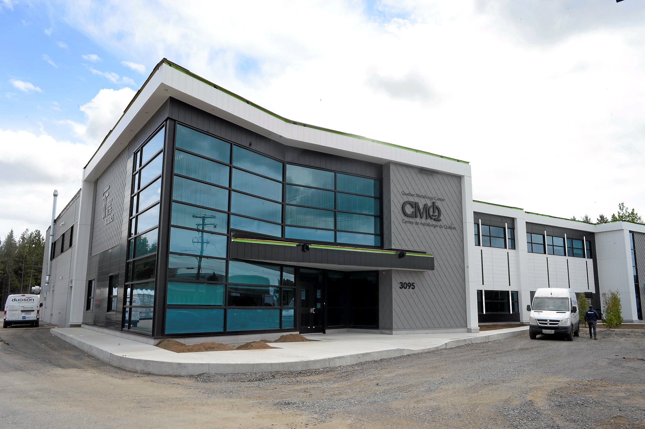 Bâtiment contemporain à deux étages avec une façade vitrée, identifié comme un centre technologique, situé dans une zone industrielle.