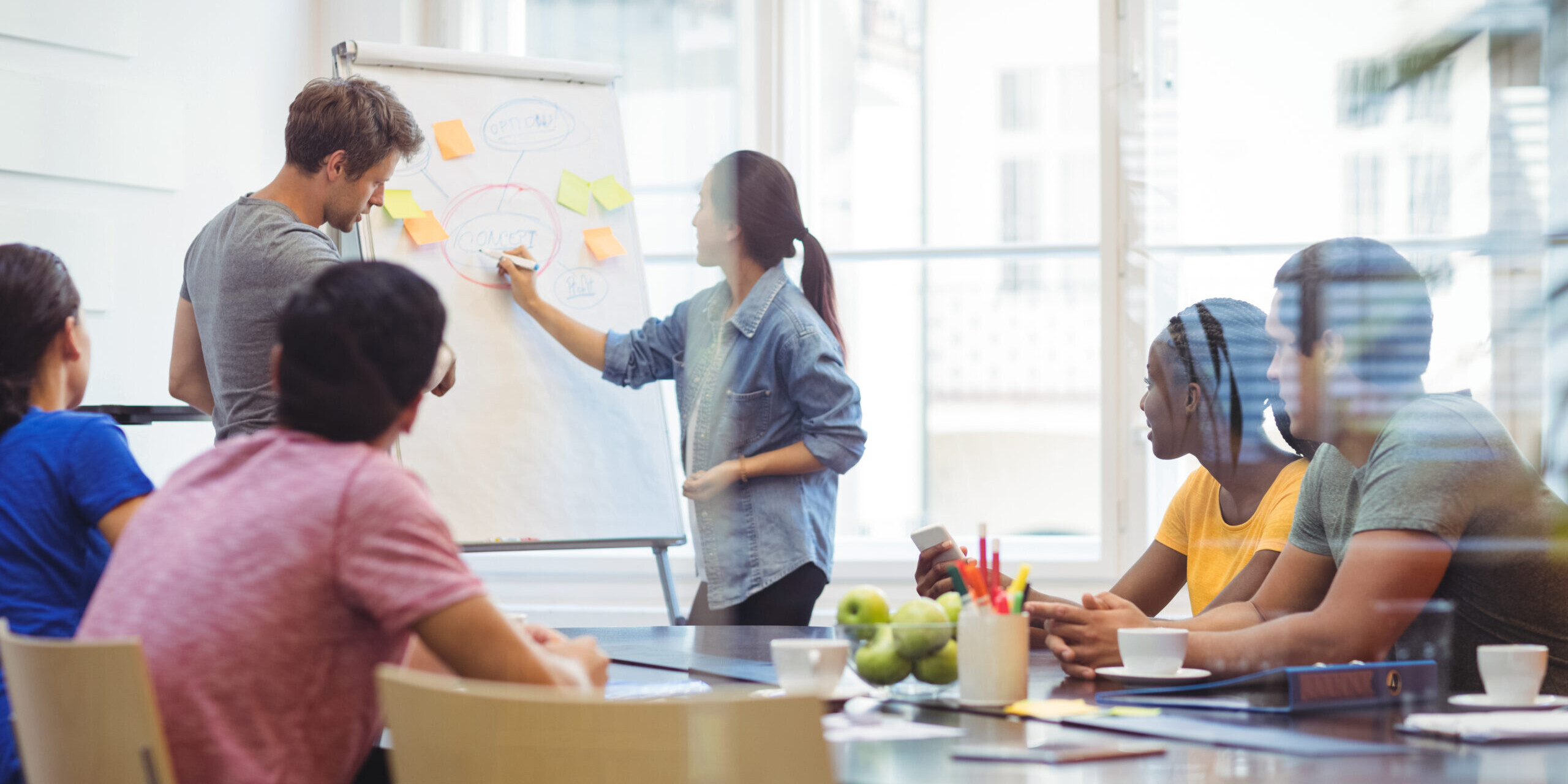 Équipe en atelier d’idéation collaboratif utilisant un tableau et des post-its pour développer une stratégie d’innovation en entreprise.