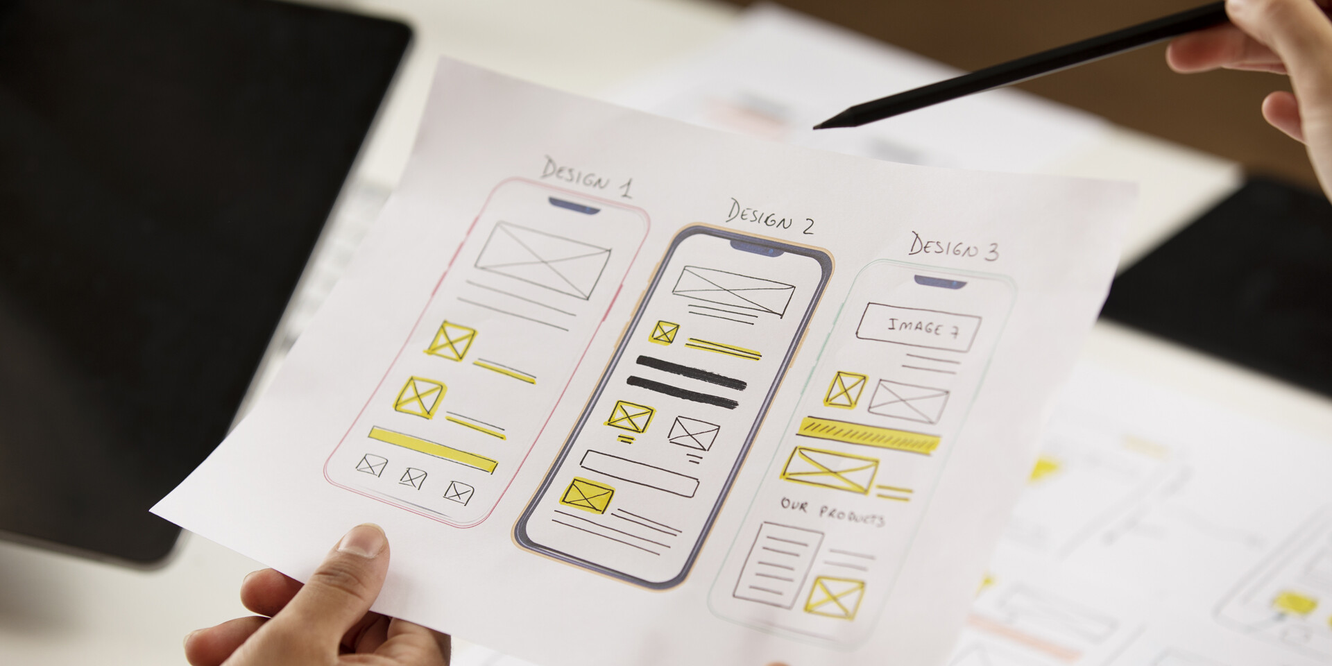 Équipe analysant trois prototypes d’interface mobile avant la commercialisation d’une innovation.