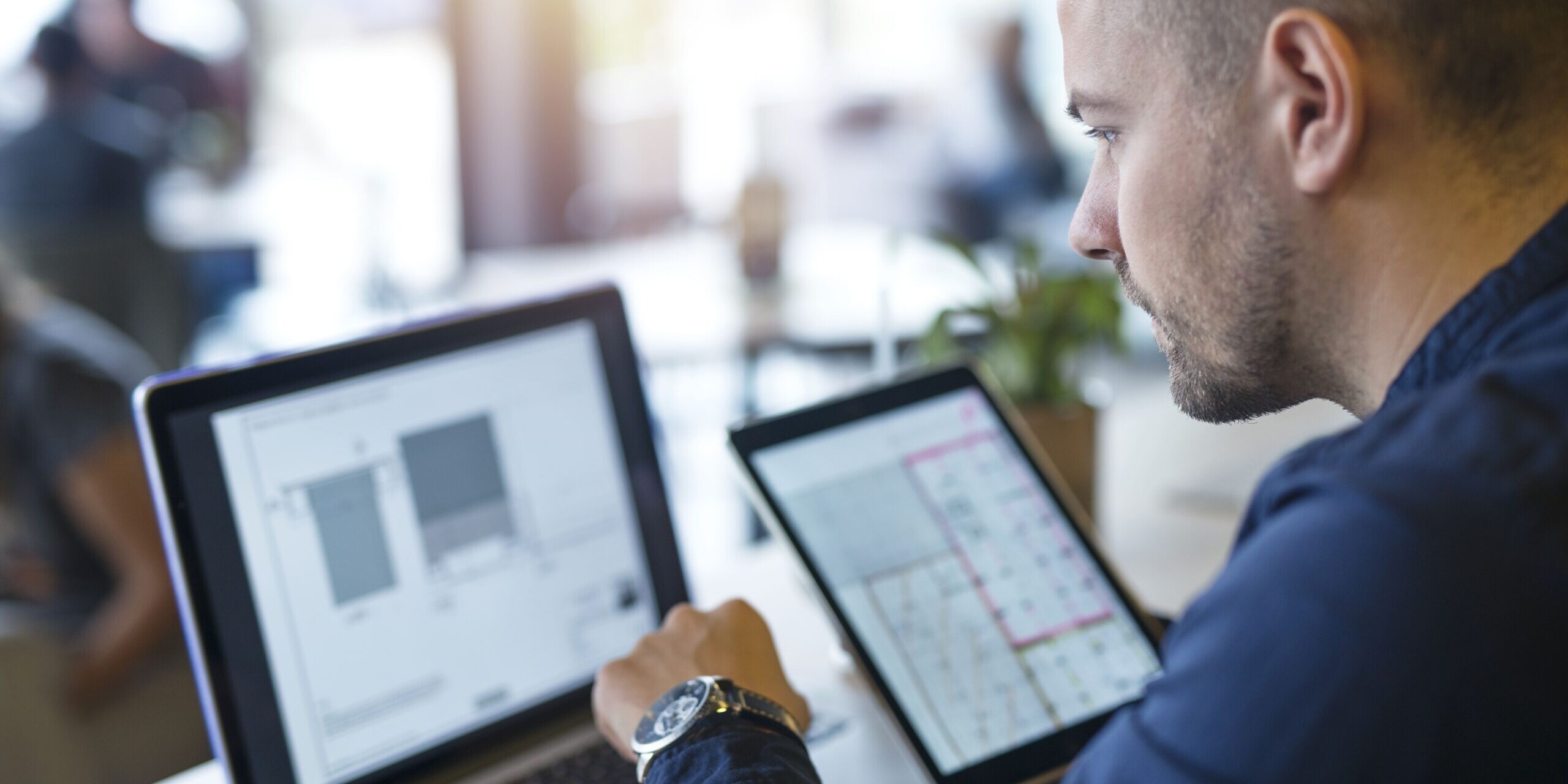 Professionnel analysant des données sur un ordinateur et une tablette dans le cadre d’un projet de transformation numérique.